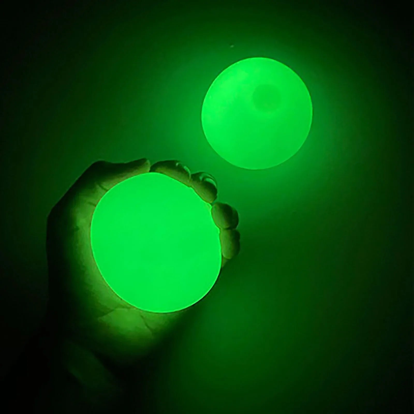 Two green glowing balls being held against a dark background